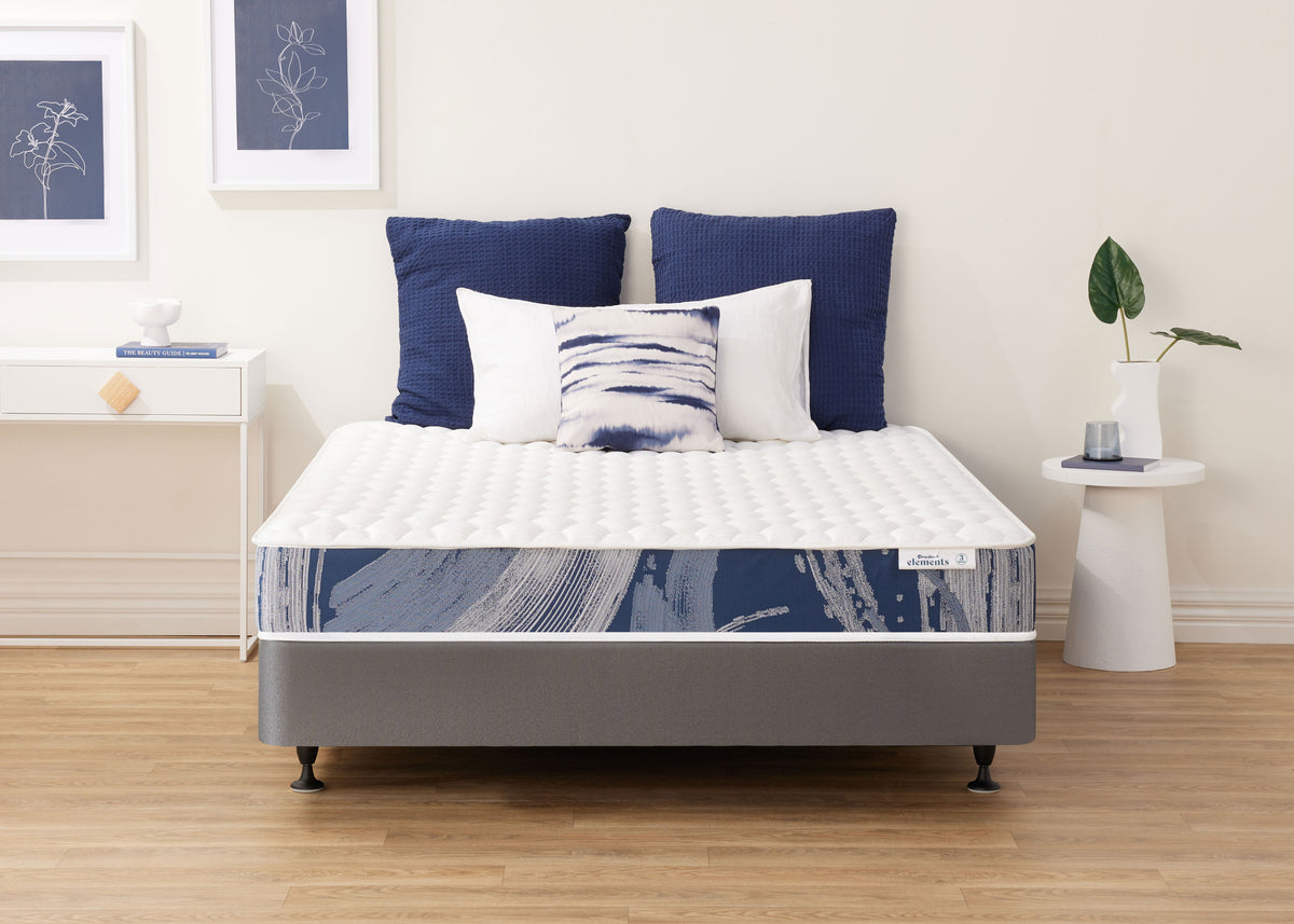 Sleepyhead Elements mattress with blue and white bedding in a room with framed art on the wall.