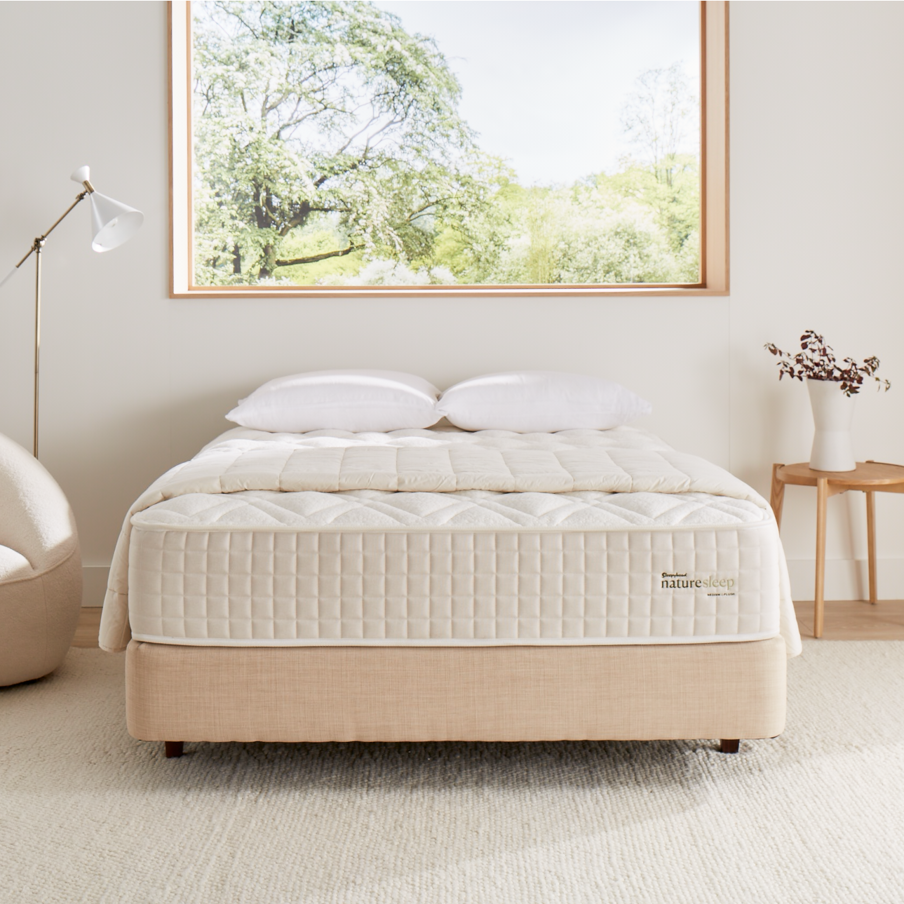 Naturesleep bed with white bedding in a bright bedroom with large window