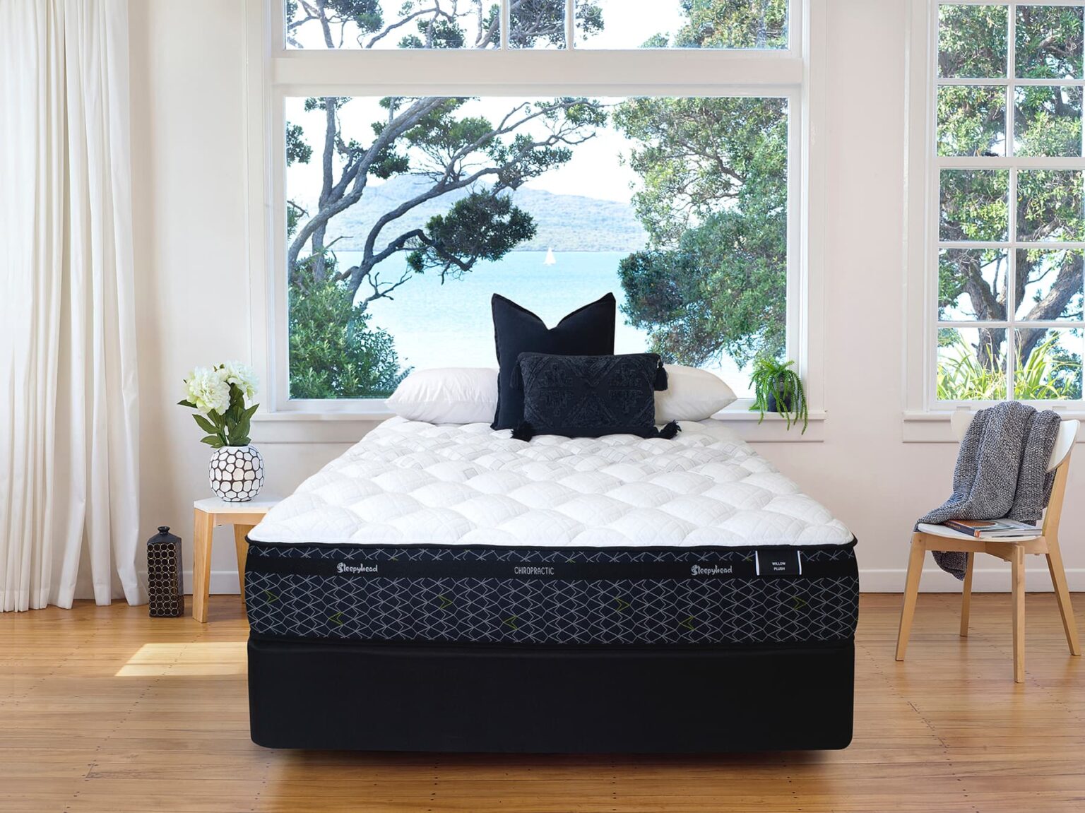 Sleepyhead Chiropractic bed with black and white mattress in a room with large windows and plants.