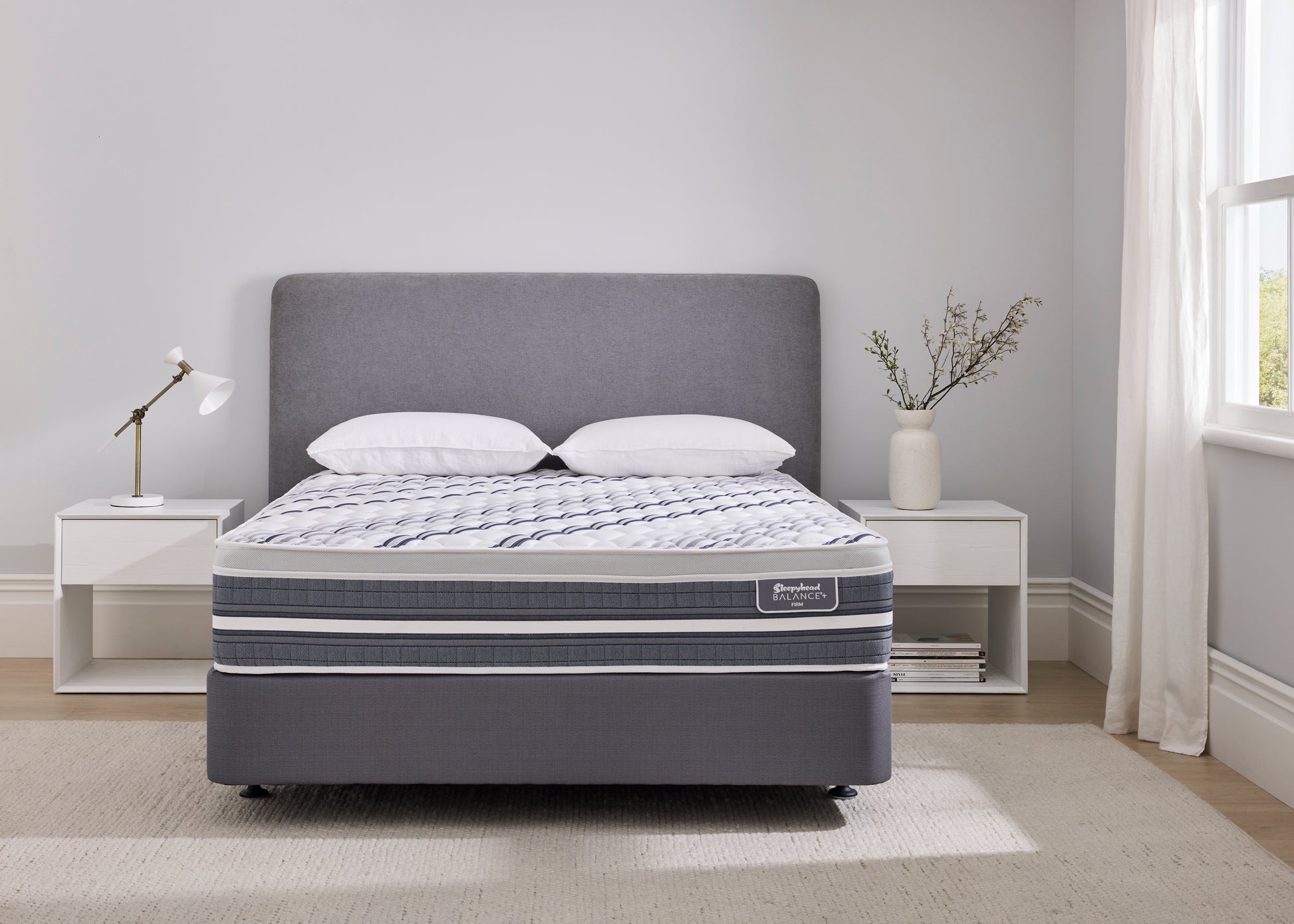 Gray upholstered Sleepyhead Balance+ bed with white pillows in a bedroom setting.