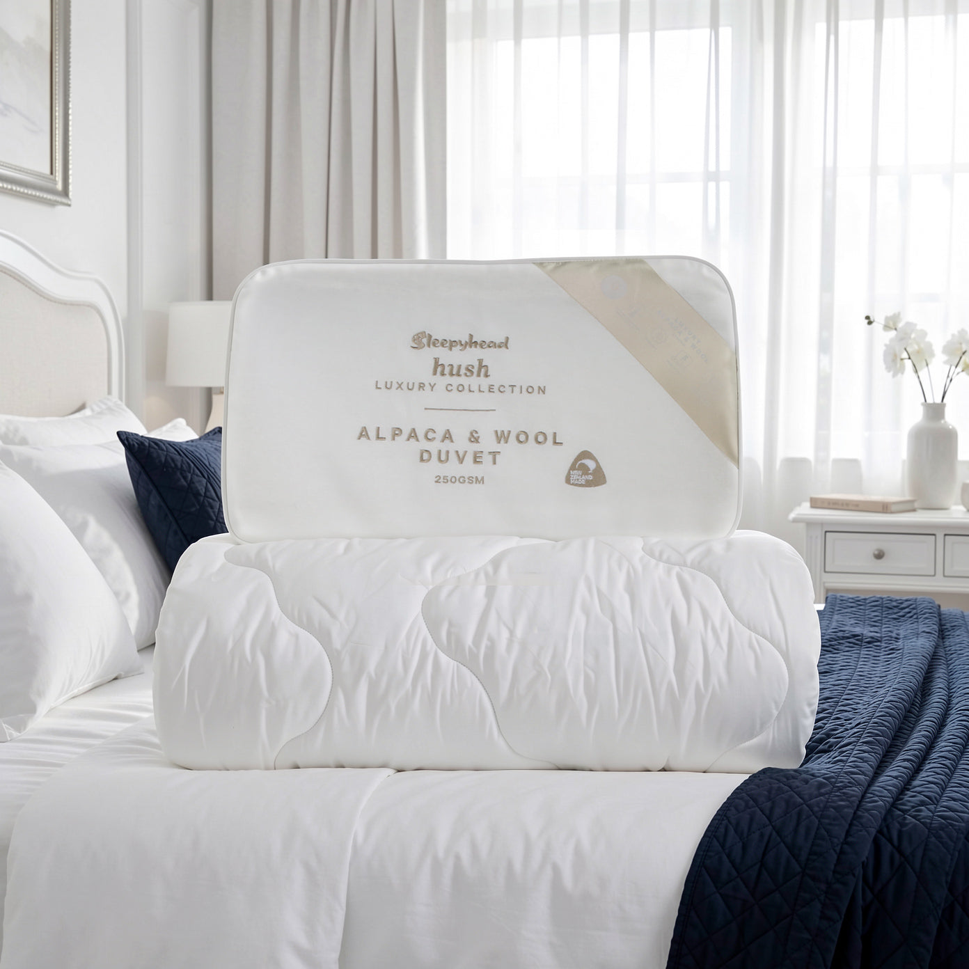 White alpaca and wool duvet on a bed with 'Sleepyhead' branding.
