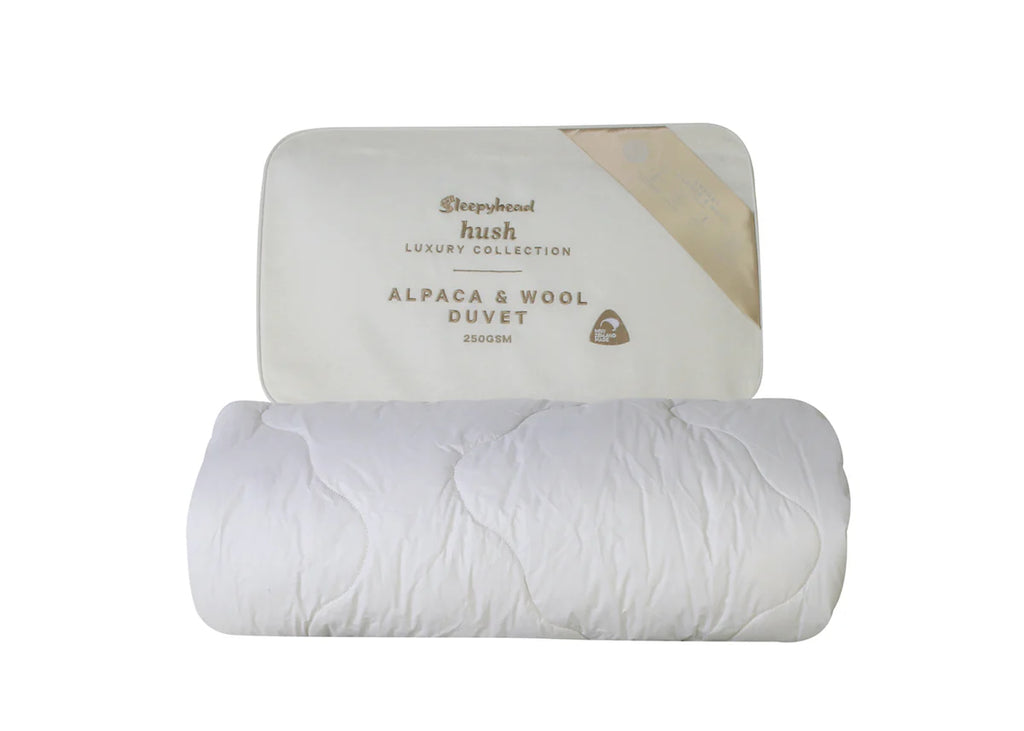 Roll of white alpaca and wool duvet with Sleepyhead Hush packaging on a white background