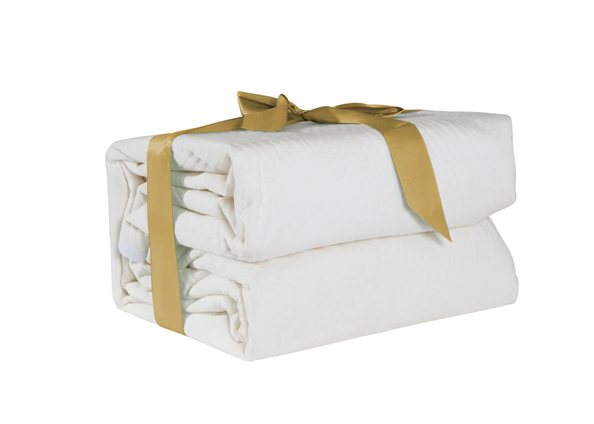 Folded white Sleepyhead mattress protector tied with a gold ribbon on a white background