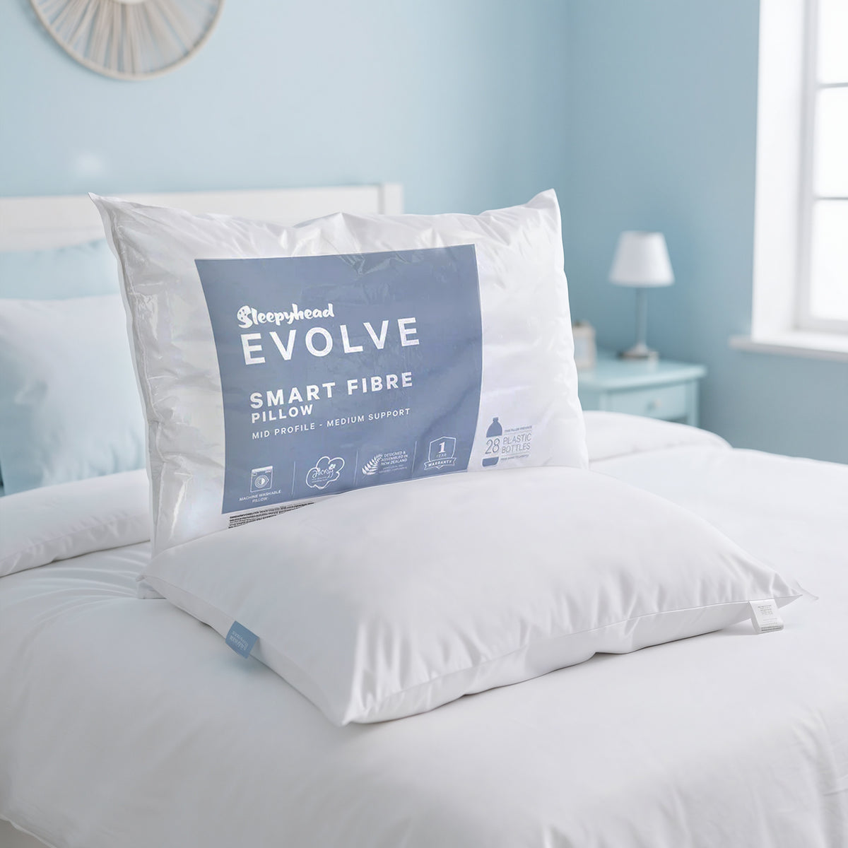 Sleepyhead Evolve smart fibre pillow on a bed with a light blue wall in the background.