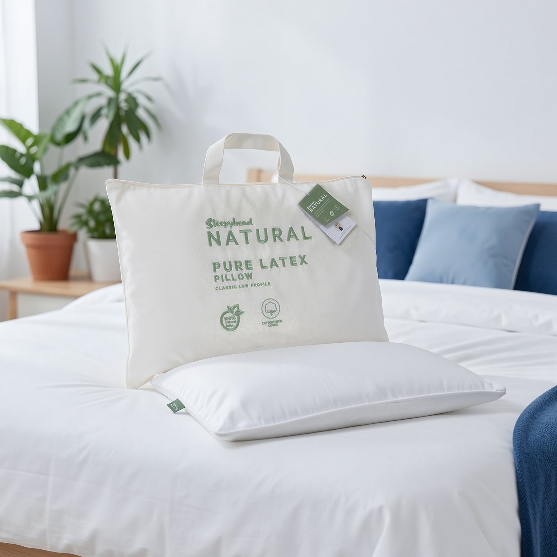 Sleepyhead Natural Pure Latex Pillow on a bed with a white pillowcase and blue pillows.