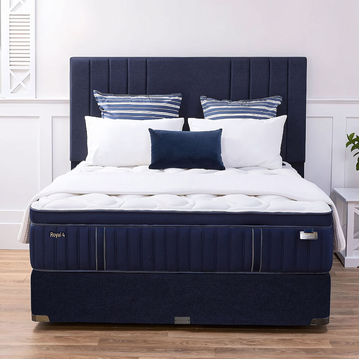 Sleepyhead Sanctuary After Dark Royal mattress with white bedding and striped pillows on a wooden floor.