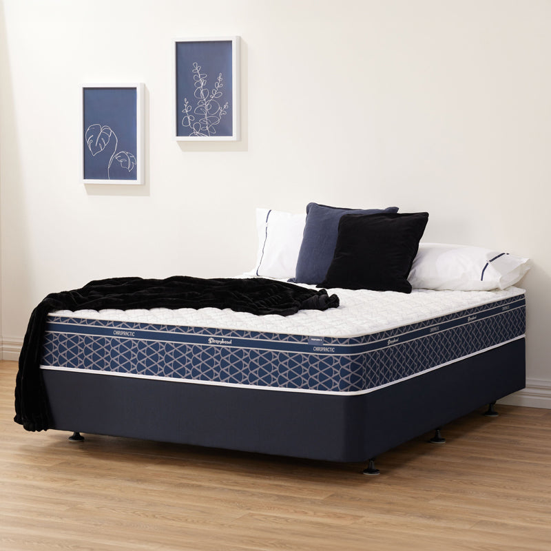 Blue Sleepyhead Chiropractic mattress with bedding and pillows in a room with framed art on the wall.