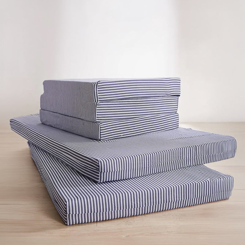 Stack of striped foam crashpads on a wooden floor.