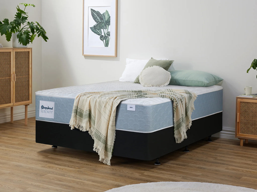 Sleepyhead Serenity bed with a blanket and pillows in a room with wooden flooring and a plant.